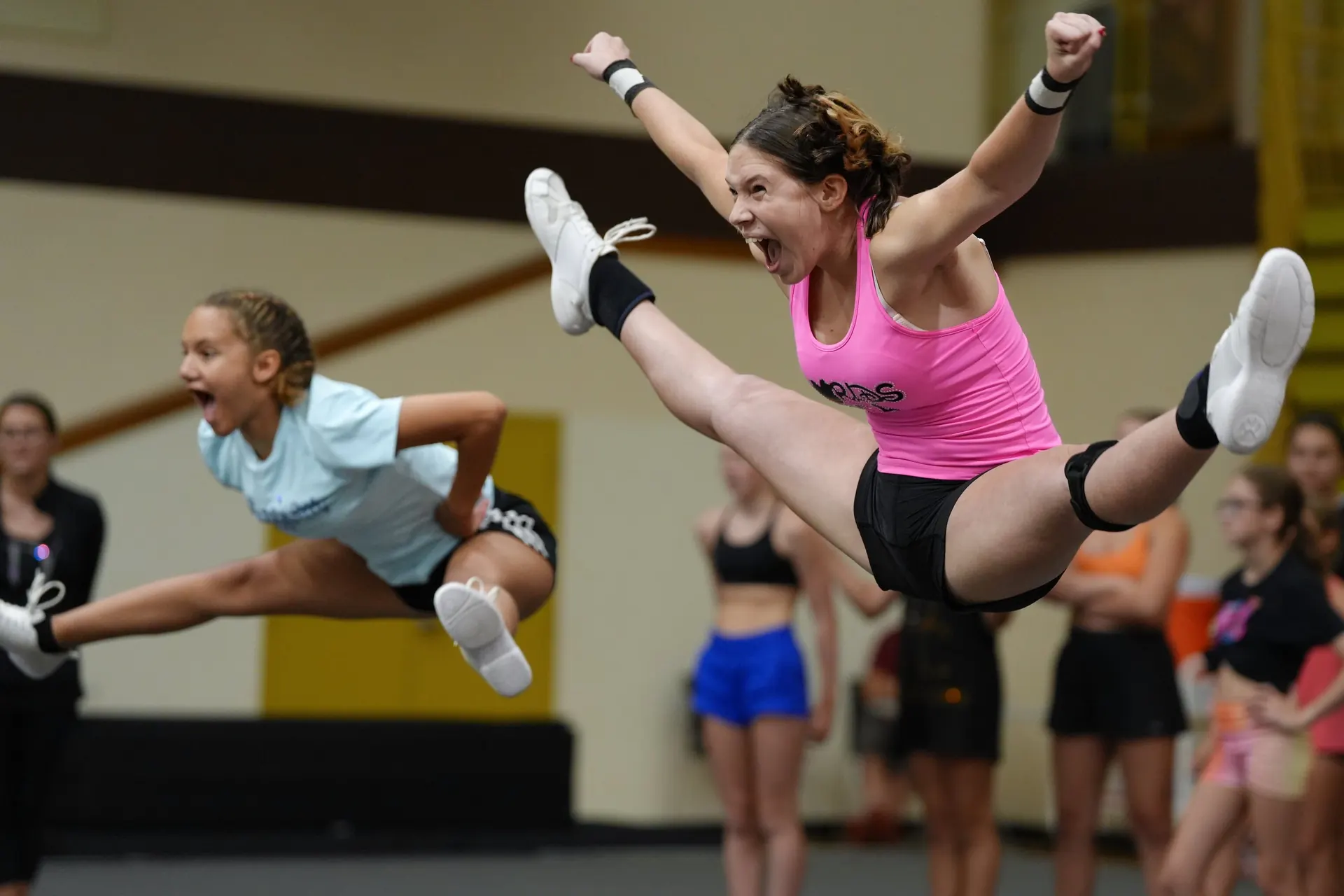 Two athletes mid-jump during a camp session